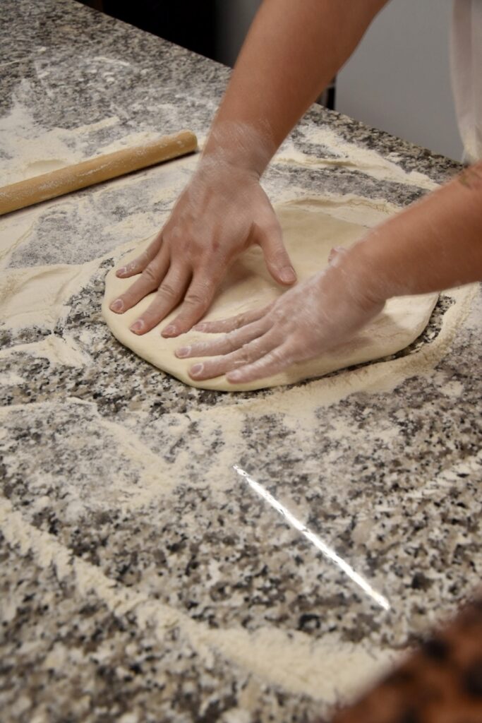 mani in pasta che lavorano l'impasto base della pizza