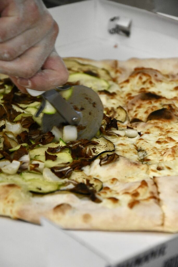 taglio di una pizza vegetariana da asporto